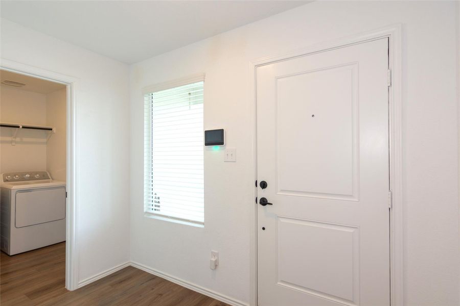 Entryway featuring a paneled door with matte black hardware, wood-finish flooring, and a window with horizontal blinds
