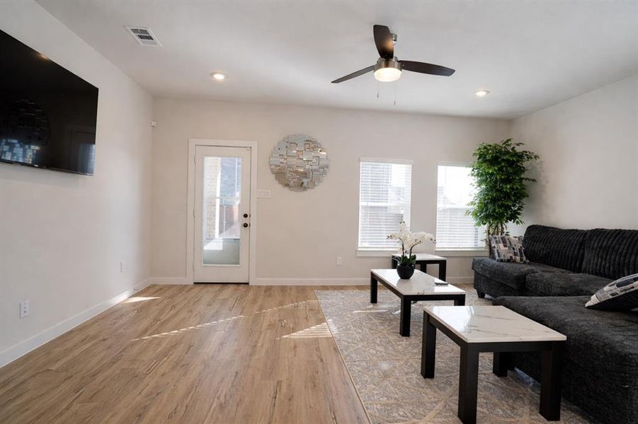 Living area with light wood finished floors, a ceiling fan, and recessed lighting