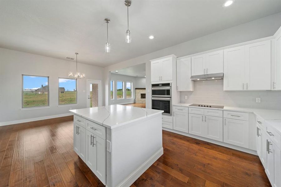 Kitchen with white cabinets, pendant lighting, backsplash, a kitchen island, and dark hardwood / wood-style flooring