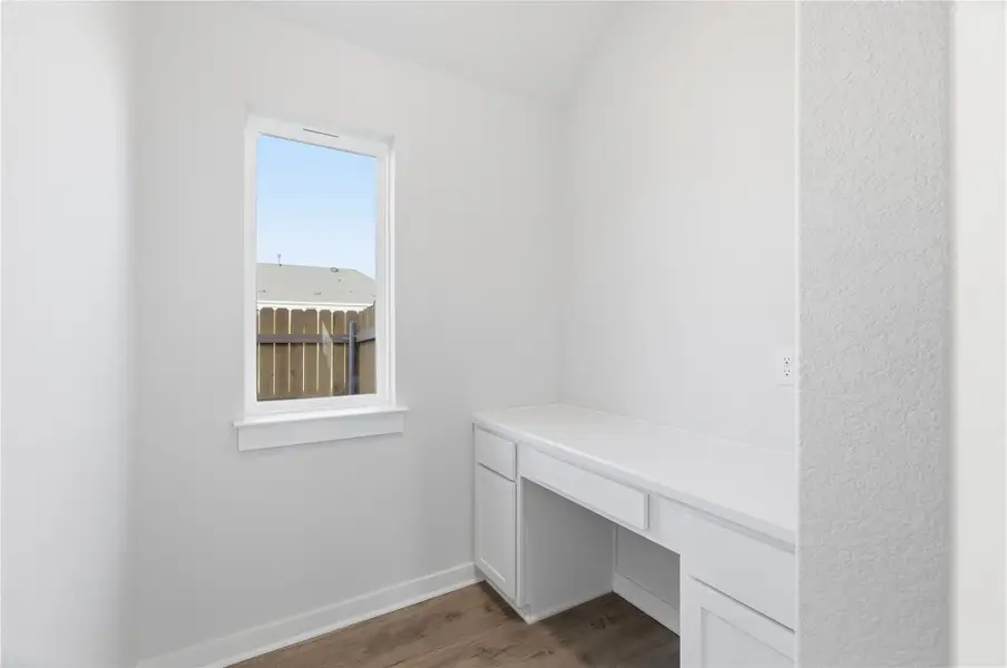 Unfurnished office with built in desk and dark wood-type flooring