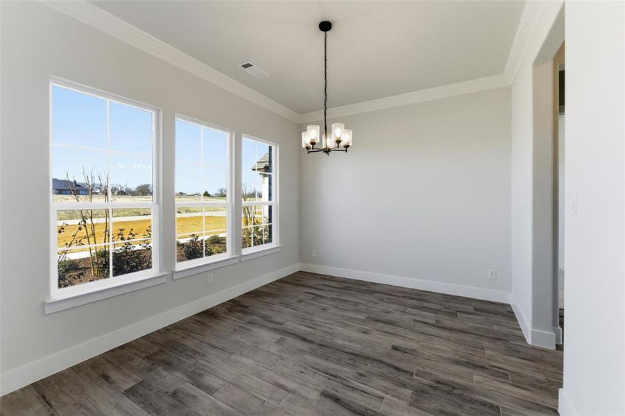 Unfurnished dining area with crown molding, a chandelier, and dark wood finished floors