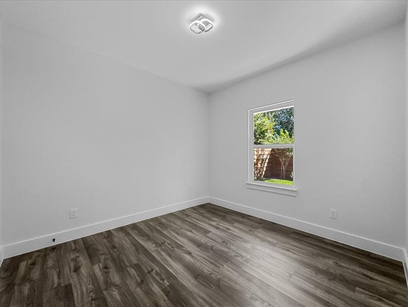 Empty room with baseboards and dark wood-style flooring Empty room with baseboards and dark wood-style flooring