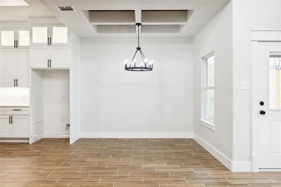 Unfurnished dining area featuring coffered ceiling and an inviting chandelier