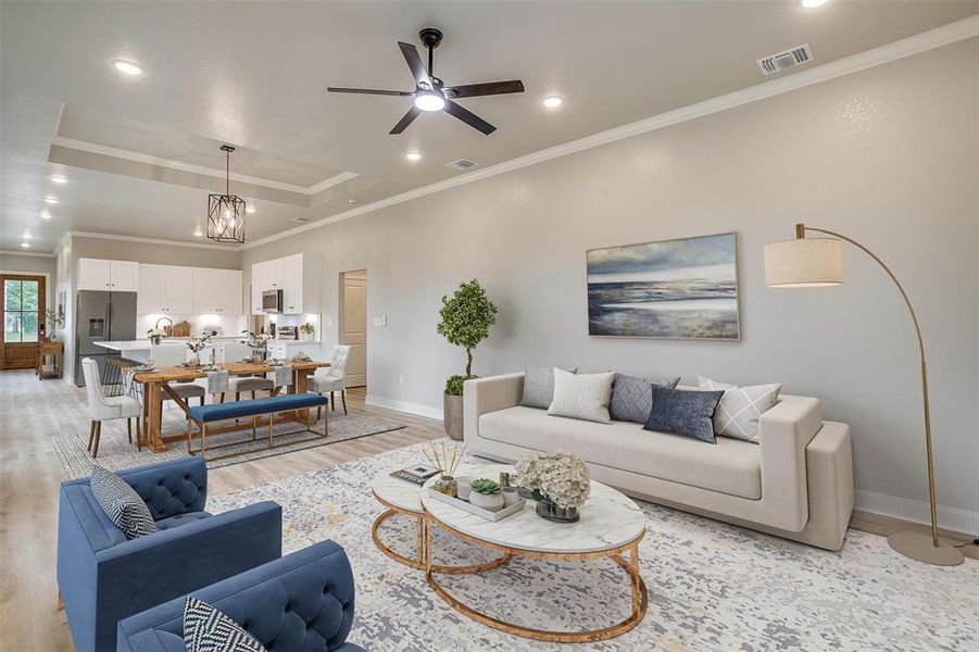 Living room with visible vents, crown molding, baseboards, light wood finished floors, and a tray ceiling Living room with visible vents, crown molding, baseboards, light wood finished floors, and a tray ceiling