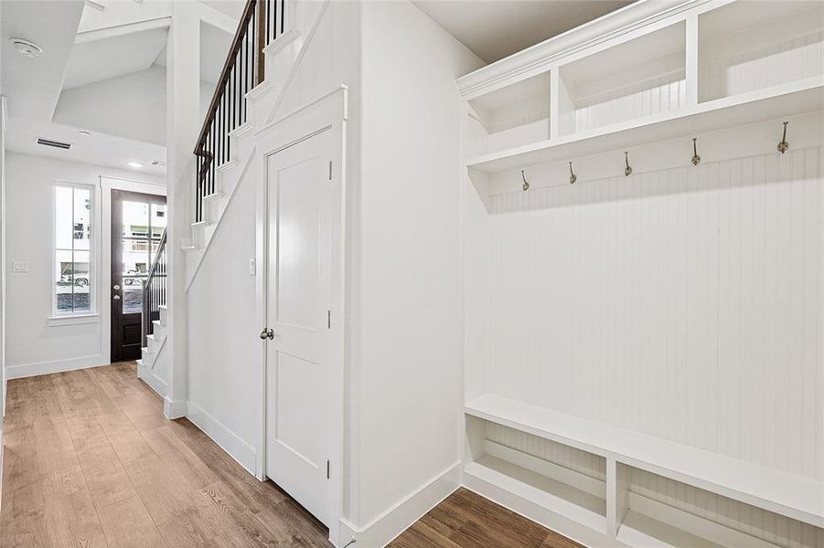 Mudroom with light wood-style floors and lofted ceiling