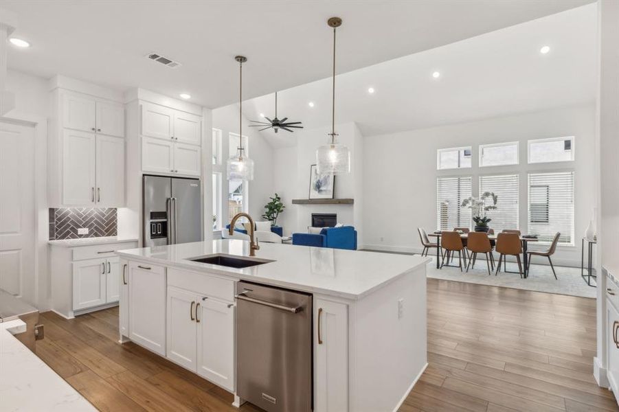 Kitchen with white cabinetry, an island with sink, light hardwood / wood-style floors, appliances with stainless steel finishes, and sink