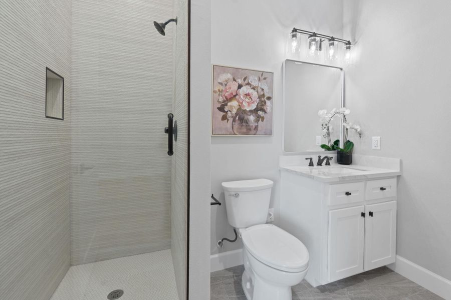 Full bathroom featuring vanity, a tile shower, and tile patterned floors