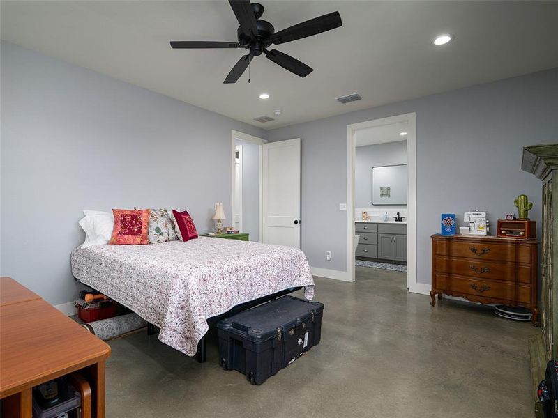 Bedroom with finished concrete floors, recessed lighting, ceiling fan, and ensuite bathroom Bedroom with finished concrete floors, recessed lighting, ceiling fan, and ensuite bathroom