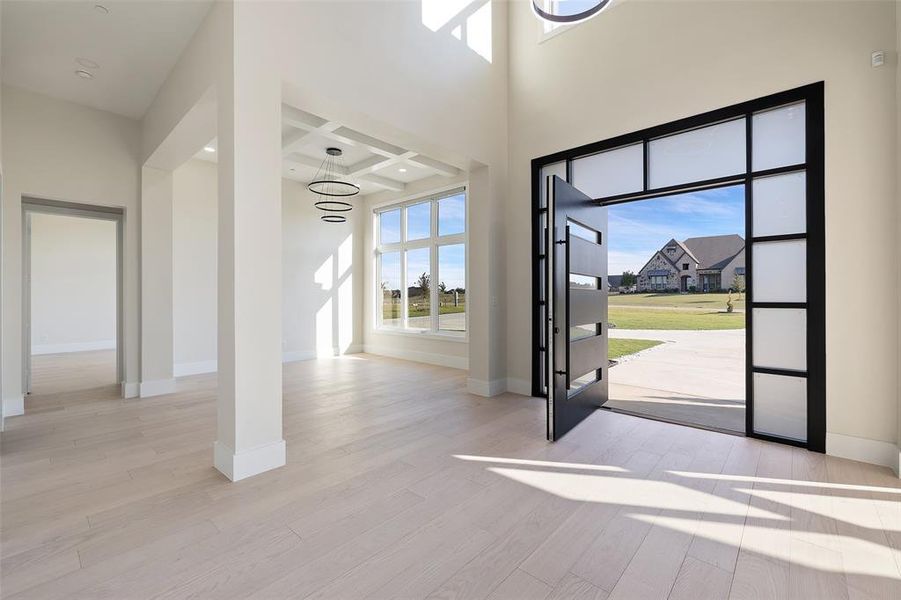 Entryway with coffered ceiling, a notable chandelier, light hardwood / wood-style flooring, and beam ceiling