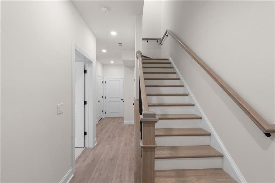 Stairway featuring wood finished floors and recessed lighting