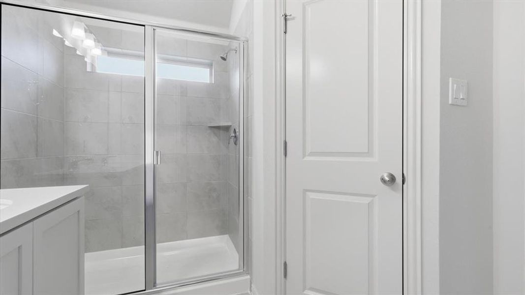 Shower enclosure featuring a sliding glass door, tiled walls, and a built-in shelf