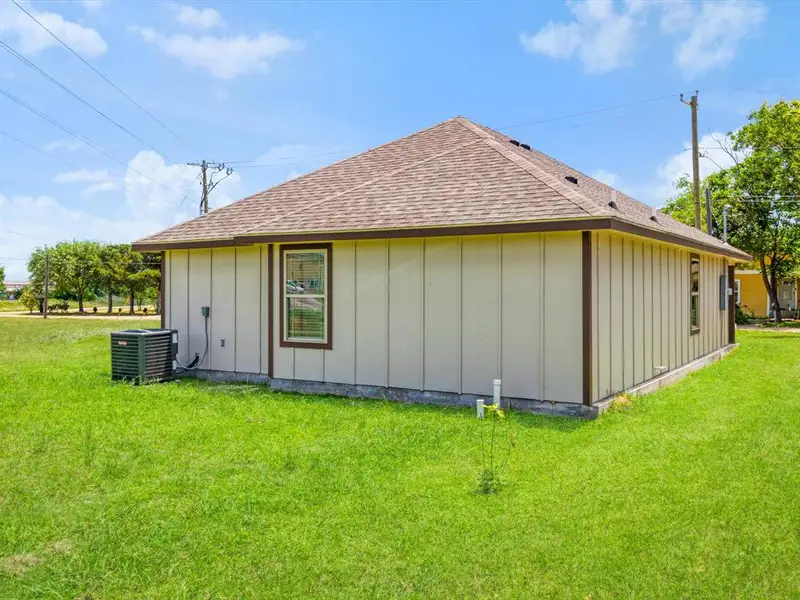 Exterior featuring light-colored vertical siding with dark brown trim, a pitched shingle roof, and a visible HVAC unit