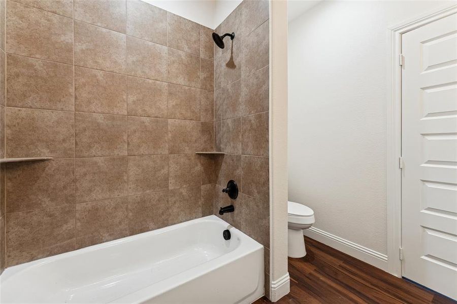 Bathroom featuring dark wood-style flooring and washtub / shower combination