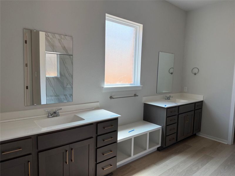 Full bathroom with two vanities, light wood-type flooring, and a marble finish shower Full bathroom with two vanities, light wood-type flooring, and a marble finish shower