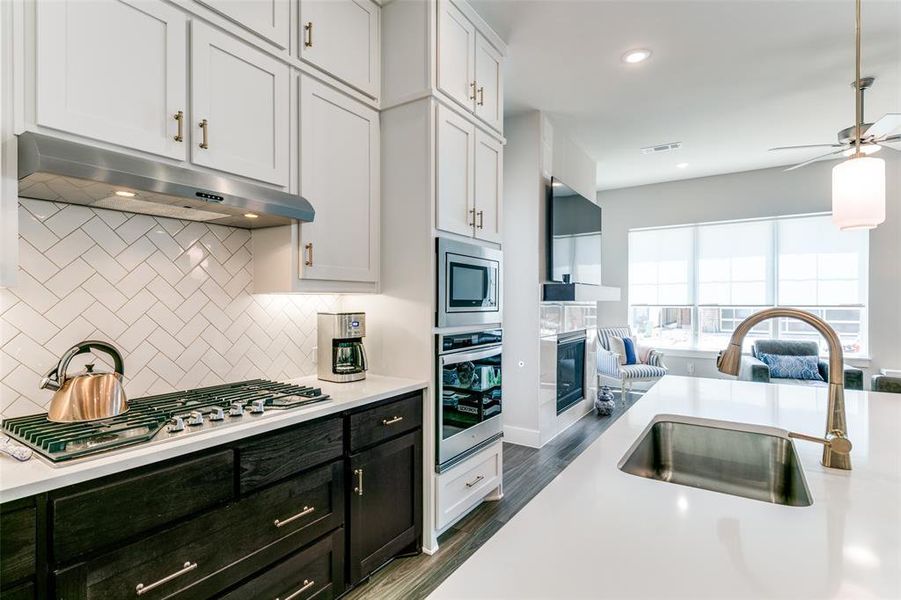 Kitchen with appliances with stainless steel finishes, dark hardwood / wood-style flooring, backsplash, sink, and white cabinetry