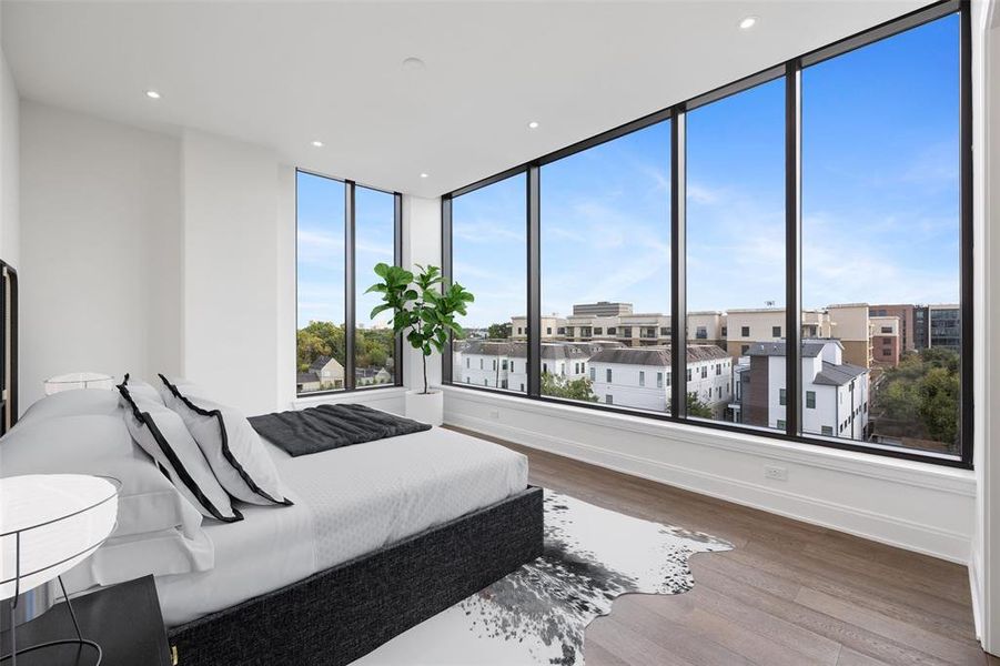 Primary bedroom with south facing windows.  Beautiful wide plank wood floors, tall ceilings, and recessed lighting.