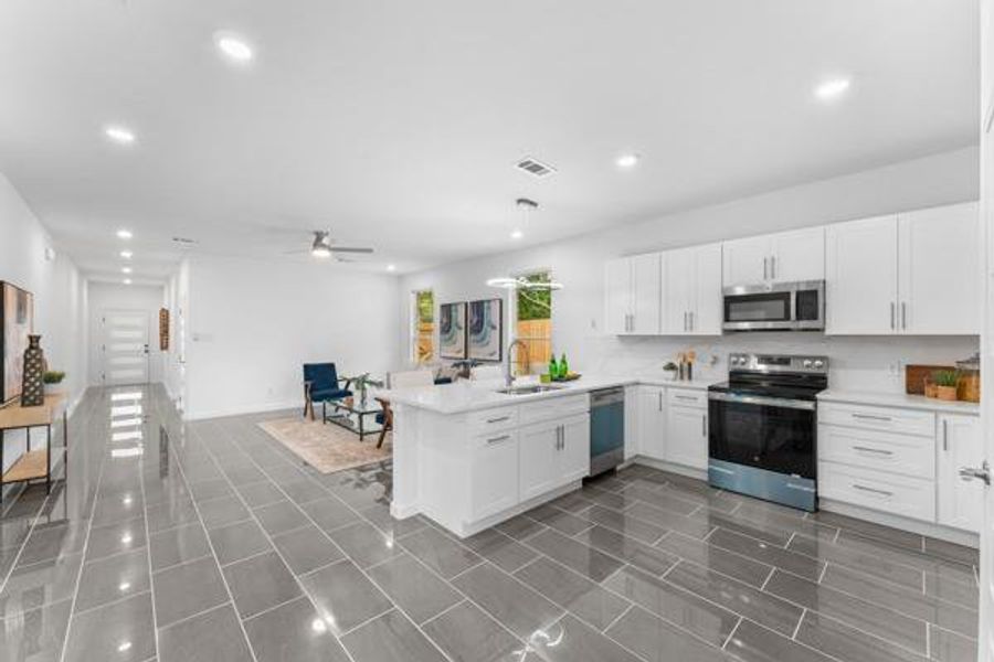 Kitchen featuring white cabinets, stainless steel appliances, open floor plan, a peninsula, and recessed lighting Kitchen featuring white cabinets, stainless steel appliances, open floor plan, a peninsula, and recessed lighting