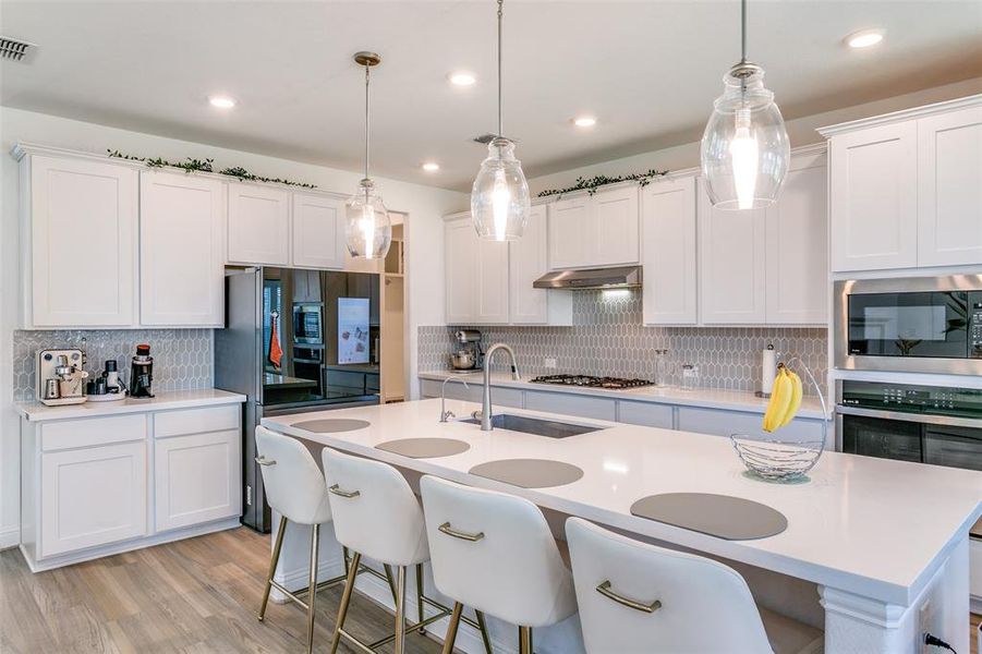 Kitchen featuring a kitchen breakfast bar, white cabinetry, backsplash, and recessed lighting