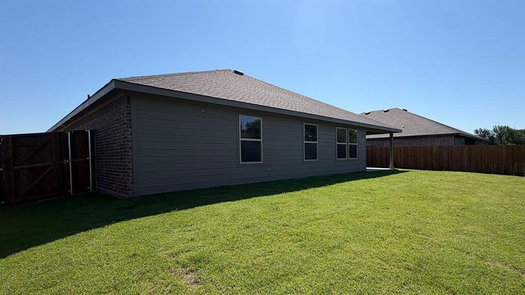 Expansive green lawn surrounds the property, featuring a privacy fence and a covered patio area Expansive green lawn surrounds the property, featuring a privacy fence and a covered patio area