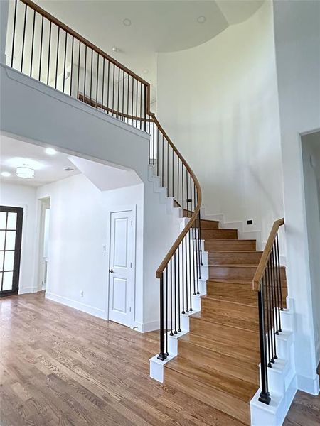 Stairs featuring a towering ceiling and wood-type flooring