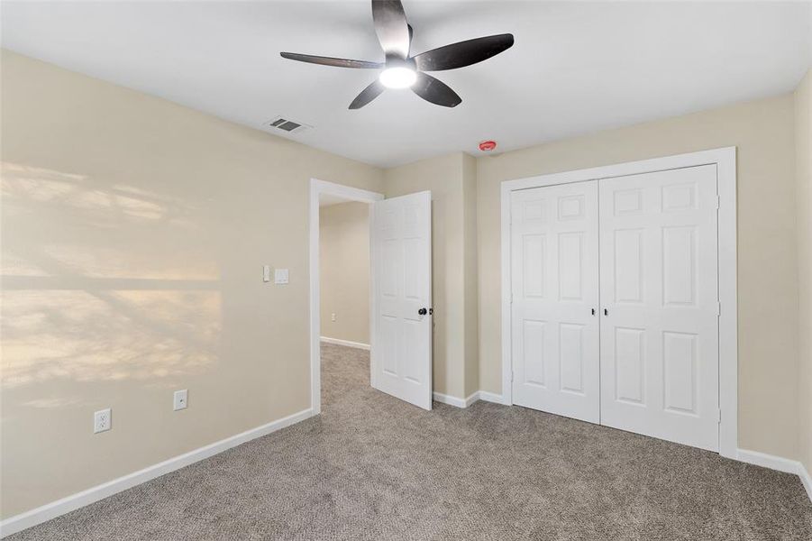 Unfurnished bedroom with a closet, light colored carpet, and ceiling fan