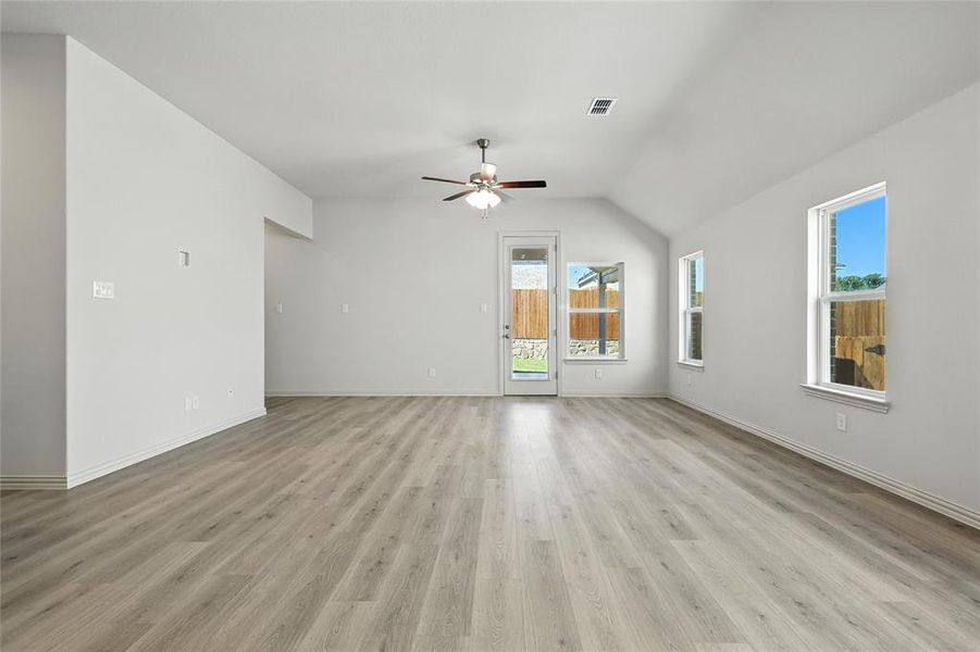 Unfurnished living room with a ceiling fan, light wood-style flooring, and lofted ceiling Unfurnished living room with a ceiling fan, light wood-style flooring, and lofted ceiling