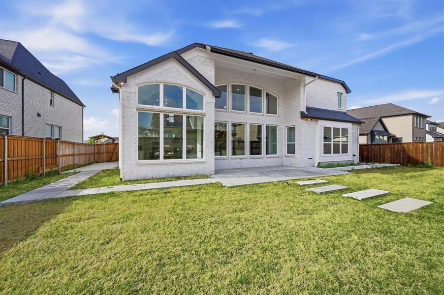 Rear exterior showcasing a expansive lawn, a concrete patio, and stepping stones