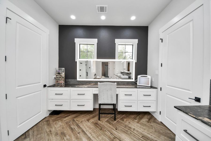 Elegant vanity area with ample storage, featuring sleek white cabinetry, a spacious countertop, and warm wood flooring for a luxurious touch.