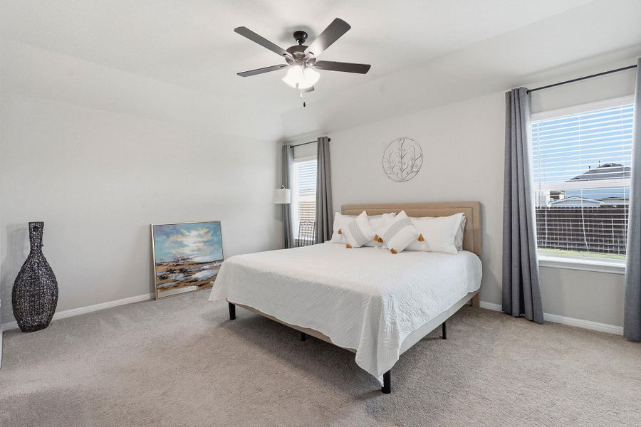 Bedroom featuring light colored carpet, a ceiling fan, and vaulted ceiling Bedroom featuring light colored carpet, a ceiling fan, and vaulted ceiling