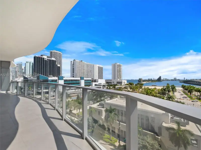 Curved balcony featuring large-format tile flooring and a glass panel railing Curved balcony featuring large-format tile flooring and a glass panel railing