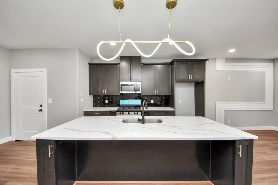 Oversized island with quartz countertops, new cabinets, backsplash and lighting.