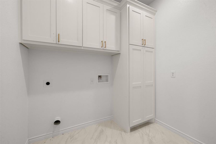 Laundry area with cabinet space, hookup for a washing machine, hookup for an electric dryer, and light marble finish floors