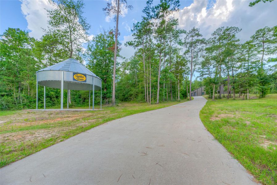 Concrete driveway leading up to the 8,200 sqft barndominium with a gazebo on the left Concrete driveway leading up to the 8,200 sqft barndominium with a gazebo on the left