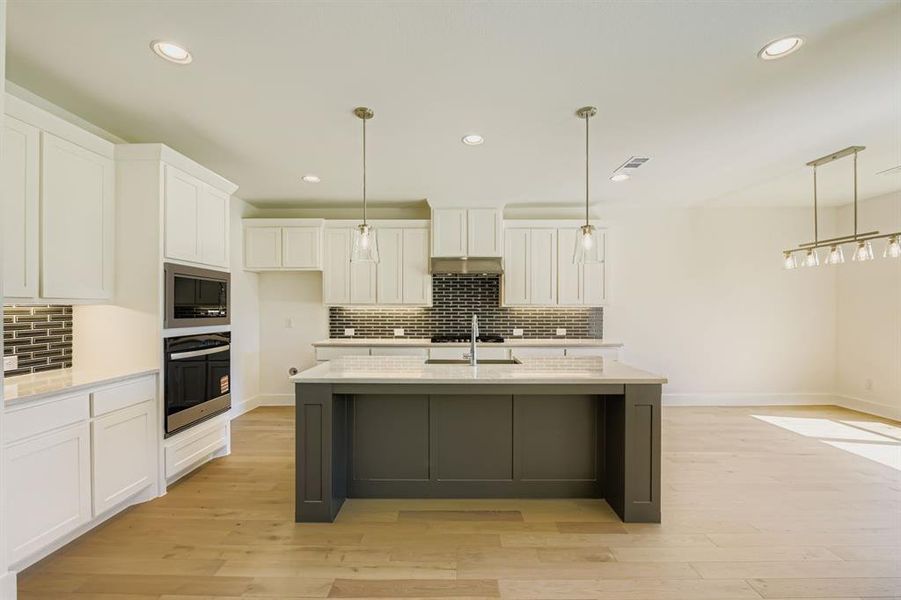 Kitchen with white cabinets, hanging light fixtures, light stone counters, and recessed lighting Kitchen with white cabinets, hanging light fixtures, light stone counters, and recessed lighting