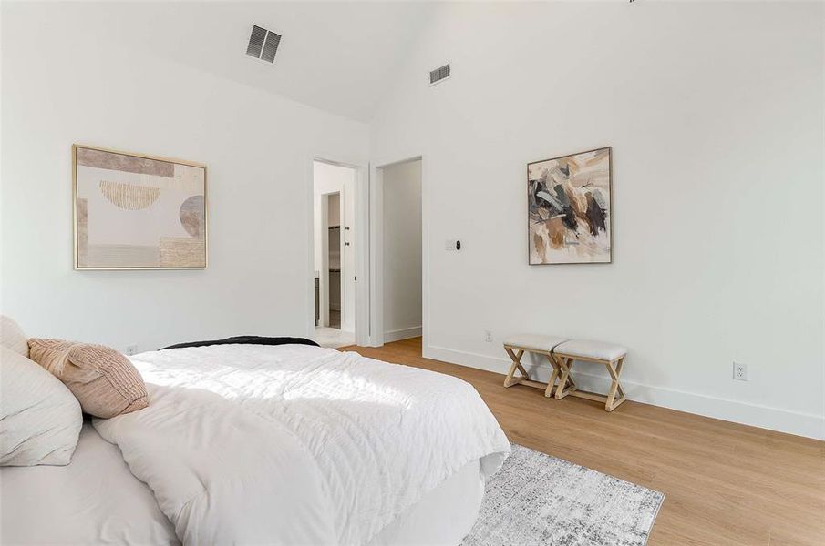 Bedroom with high vaulted ceiling and light wood-type flooring