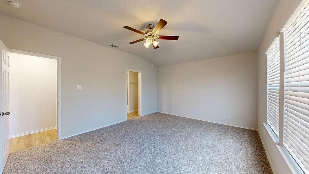 Well-lit primary bedroom features soft carpet and a convenient walk-in closet.