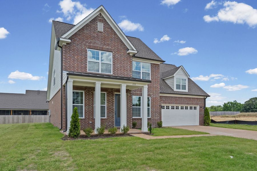 Brick facade residence with a columned front porch, multi-pane windows, and an attached two-car garage Brick facade residence with a columned front porch, multi-pane windows, and an attached two-car garage