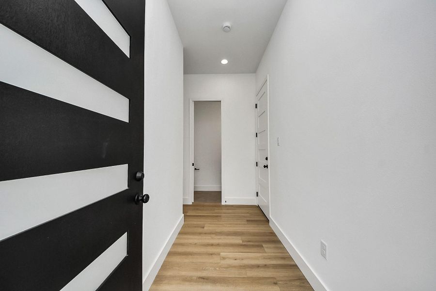 Clean and inviting front entryway featuring a modern statement door, sleek finishes, and warm wood flooring that sets the tone for the home’s contemporary design. A bright, welcoming space that creates a strong first impression from the moment you step inside.
