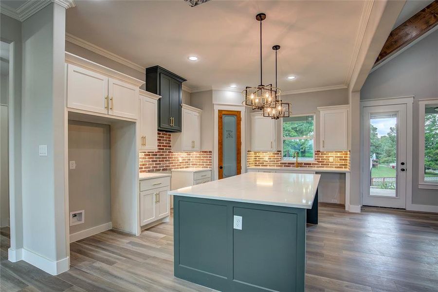 Kitchen featuring white cabinets, pendant lighting, light hardwood / wood-style floors, decorative backsplash, and a center island