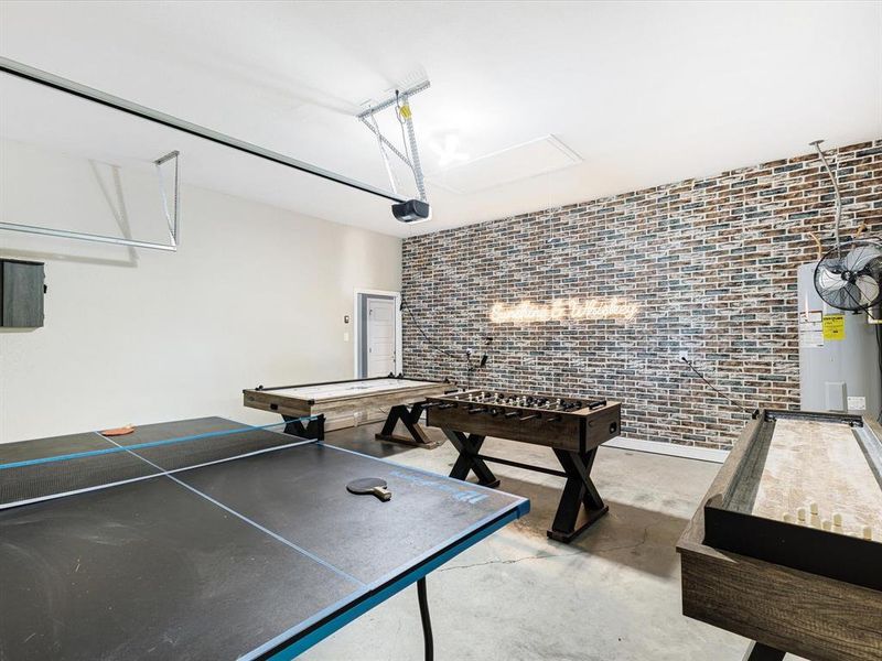 Playroom featuring concrete floors, water heater, and brick wall