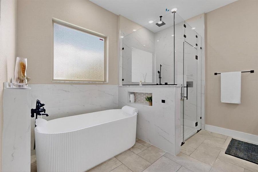 Full bathroom featuring a soaking tub, a marble finish shower, tile walls, and light tile patterned floors