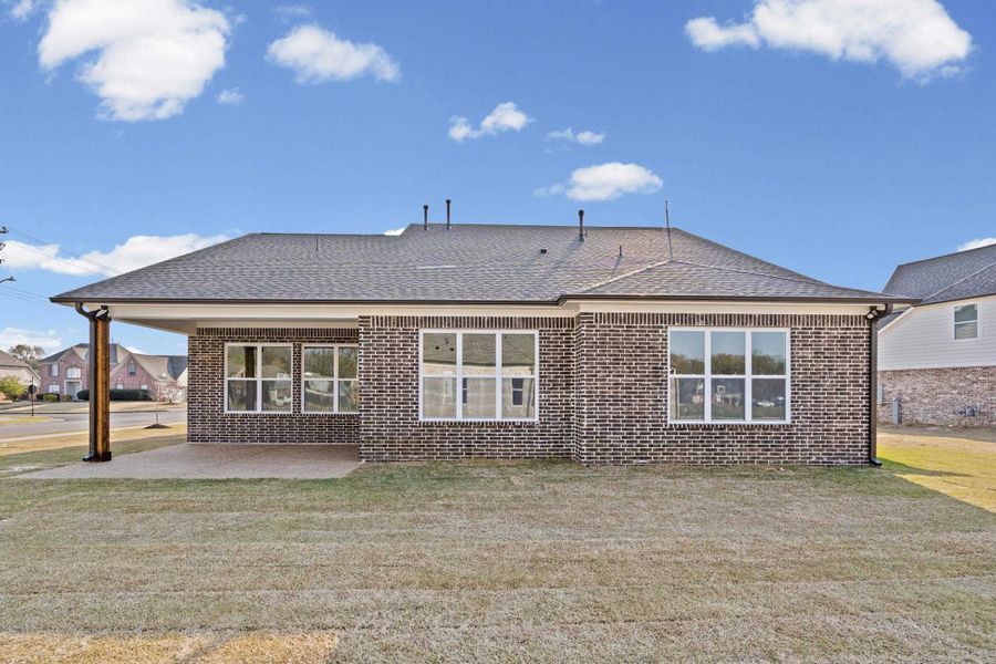 Back of house with roof with shingles, brick siding, and a yard