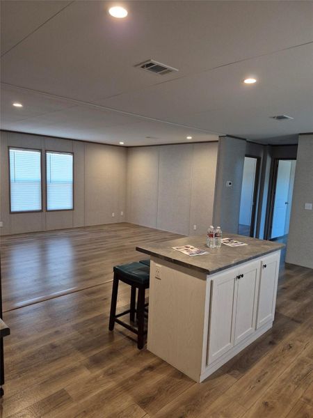 Kitchen with white cabinetry, open floor plan, a center island, dark wood-style floors, and dark countertops