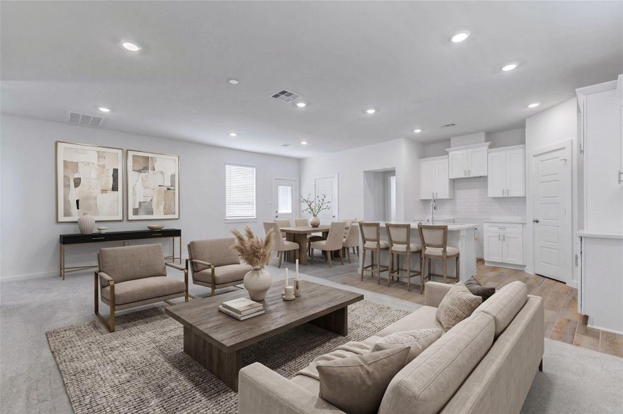 Open-concept living, dining, and kitchen area with soft carpet in the living space, wood-look tile in the kitchen, recessed lighting, white cabinetry, and a large island. The spacious layout offers flexibility for everyday living, entertaining, and comfortable furniture placement.