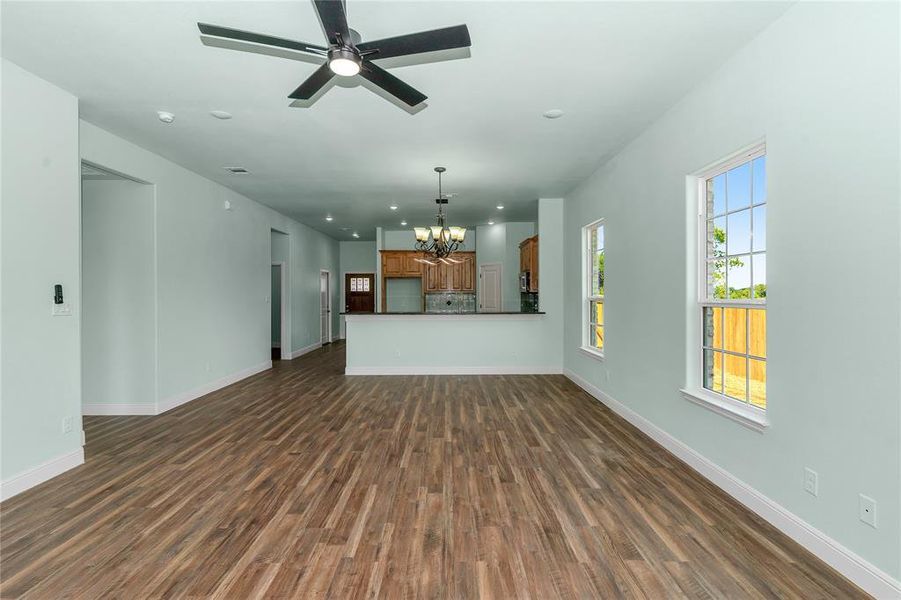 Unfurnished living room featuring dark wood finished floors, a chandelier, recessed lighting, and a ceiling fan