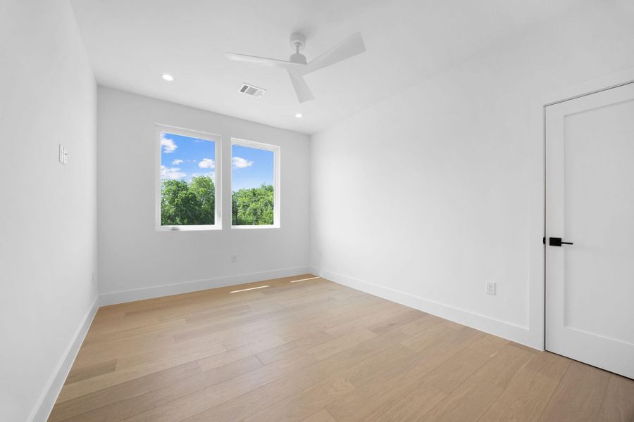 A tranquil sanctuary, this room offers light hardwood flooring and a refreshing ceiling fan.