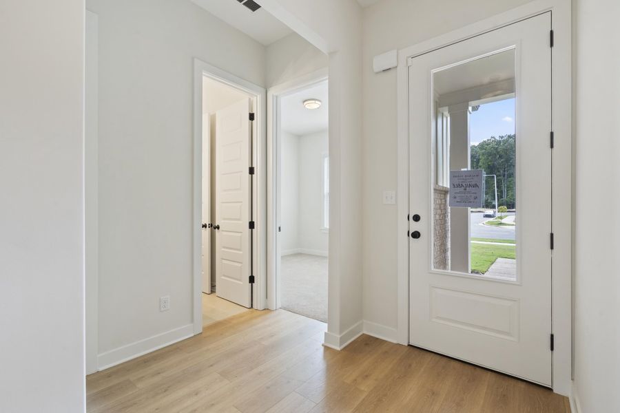 Entryway featuring wood-finish flooring, a white paneled door with a clear glass insert, and black hardware