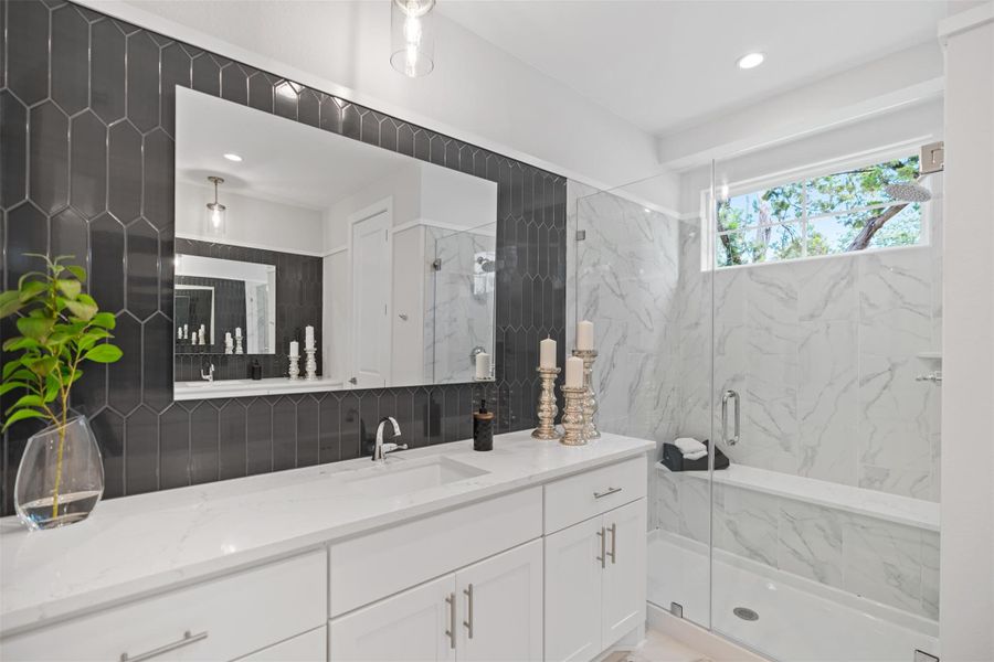 Full bath featuring a marble finish shower, vanity, and recessed lighting. The photos shown are of a completed home with the same floor plan and may not reflect the exact finishes, features, or layout of the home currently under construction.