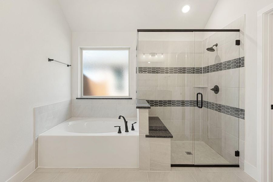 Master bathroom with soaking tub, glass-enclosed walk-in shower, tile walls, and dark hardware accents