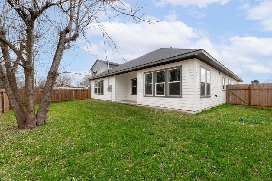 Well-maintained lawn, a large tree, and a modern white house with multiple windows. The area is enclosed by a wooden fence, providing privacy and a cozy outdoor space. Well-maintained lawn, a large tree, and a modern white house with multiple windows. The area is enclosed by a wooden fence, providing privacy and a cozy outdoor space.